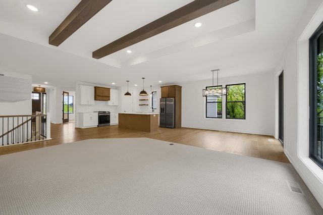 unfurnished living room with an inviting chandelier, dark wood-type flooring, plenty of natural light, and beamed ceiling