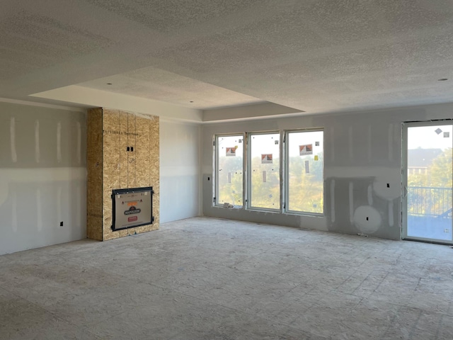 unfurnished living room featuring a fireplace, a raised ceiling, and a textured ceiling