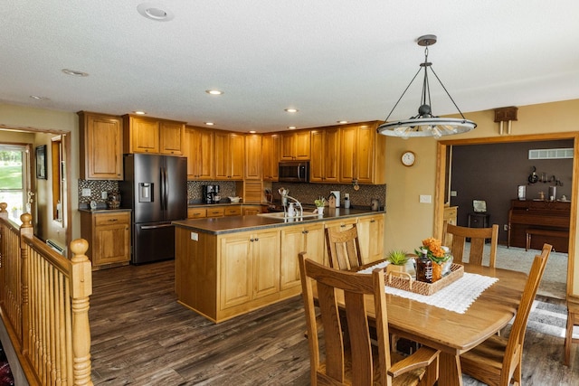 kitchen with appliances with stainless steel finishes, dark wood-type flooring, tasteful backsplash, pendant lighting, and sink