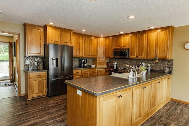 kitchen featuring a textured ceiling, kitchen peninsula, appliances with stainless steel finishes, and dark hardwood / wood-style flooring