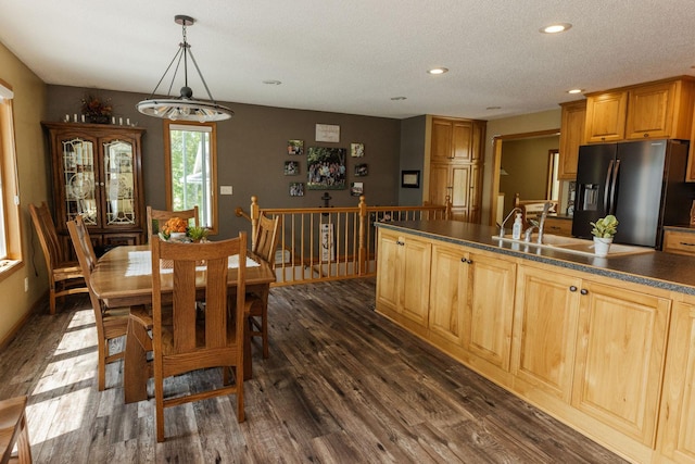 kitchen featuring a textured ceiling, stainless steel fridge with ice dispenser, sink, decorative light fixtures, and dark hardwood / wood-style flooring