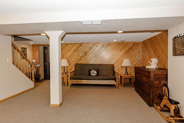 sitting room with a textured ceiling, carpet flooring, and wood walls