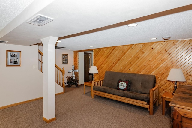 living room with a textured ceiling, wood walls, and carpet flooring