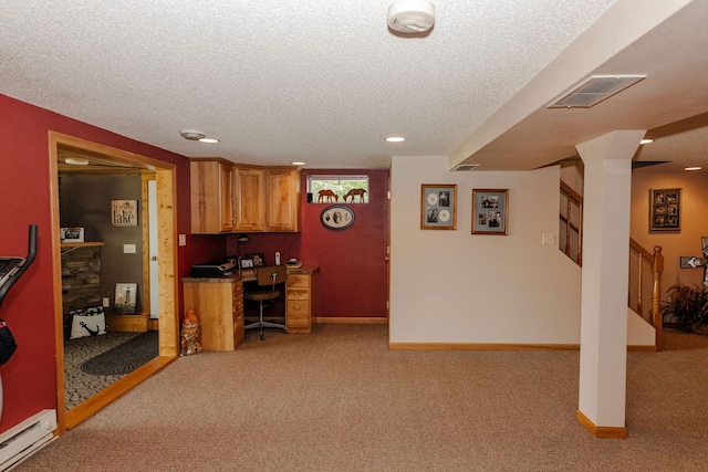 kitchen with a textured ceiling, built in desk, light colored carpet, and a baseboard radiator