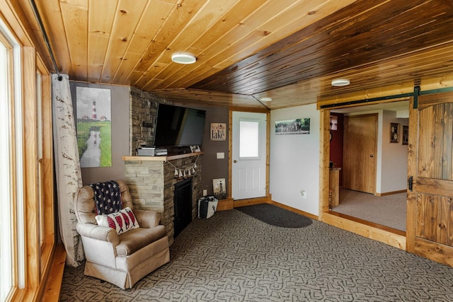 living area with a fireplace, a barn door, and wooden ceiling