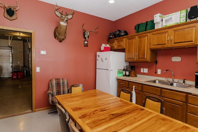 kitchen with a textured ceiling, white fridge, and sink