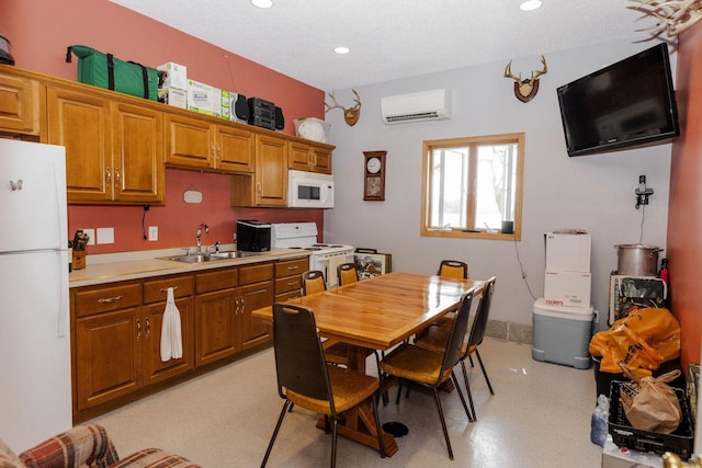 kitchen featuring white appliances, a textured ceiling, sink, and a wall mounted air conditioner