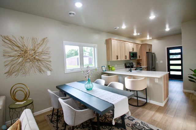 501 1st St NE, Hankinson, ND 58041 - kitchen featuring light countertops, light brown cabinets, a peninsula, light wood-style flooring, and appliances with stainless steel finishes