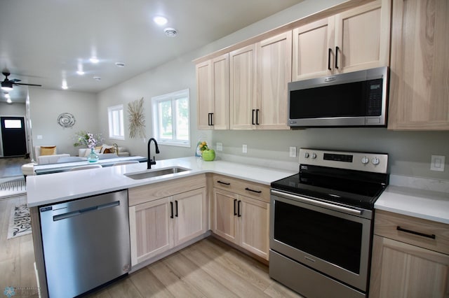 501 1st St NE, Hankinson, ND 58041 - kitchen with a peninsula, light brown cabinetry, a sink, open floor plan, and appliances with stainless steel finishes