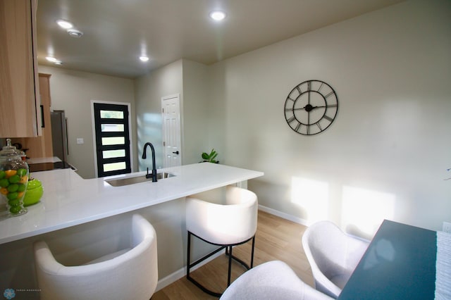 501 1st St NE, Hankinson, ND 58041 - kitchen with a peninsula, light wood-style floors, a kitchen bar, and a sink