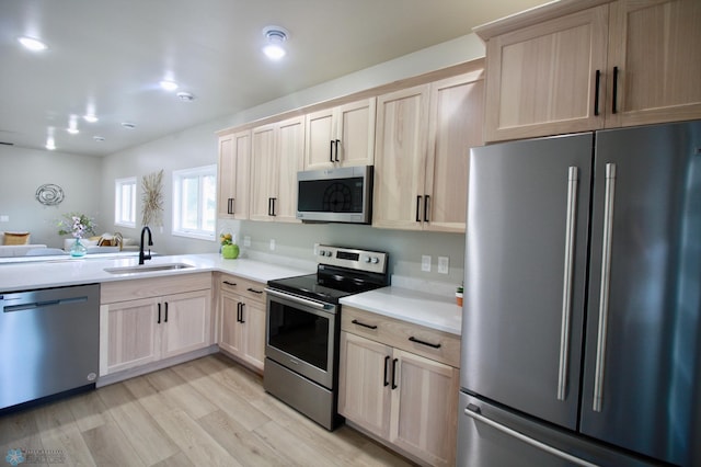 501 1st St NE, Hankinson, ND 58041 - kitchen featuring stainless steel appliances, light brown cabinetry, a sink, light wood-style floors, and light countertops