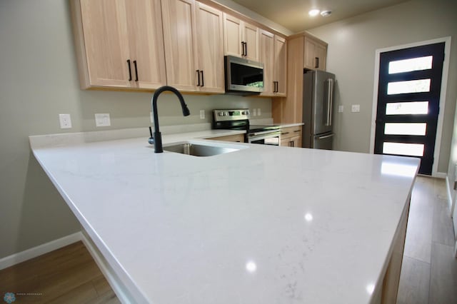 501 1st St NE, Hankinson, ND 58041 - kitchen featuring stainless steel appliances, light countertops, wood finished floors, light brown cabinets, and a sink