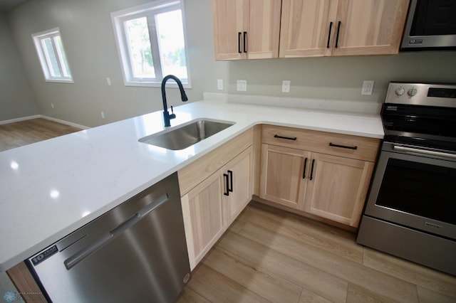 501 1st St NE, Hankinson, ND 58041 - kitchen with a sink, light brown cabinetry, light wood-type flooring, stainless steel appliances, and light countertops