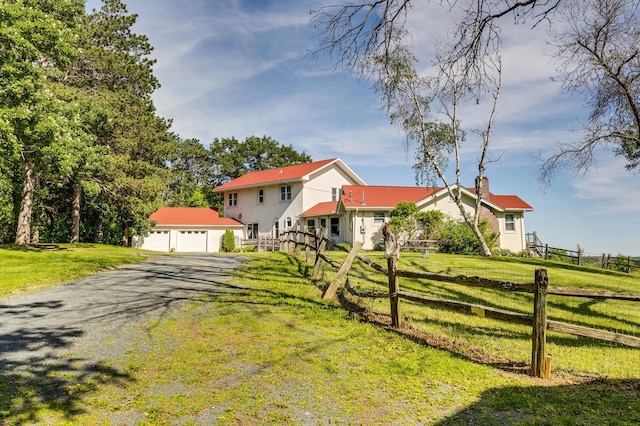 view of front of home featuring driveway, a front lawn, a chimney, and fence