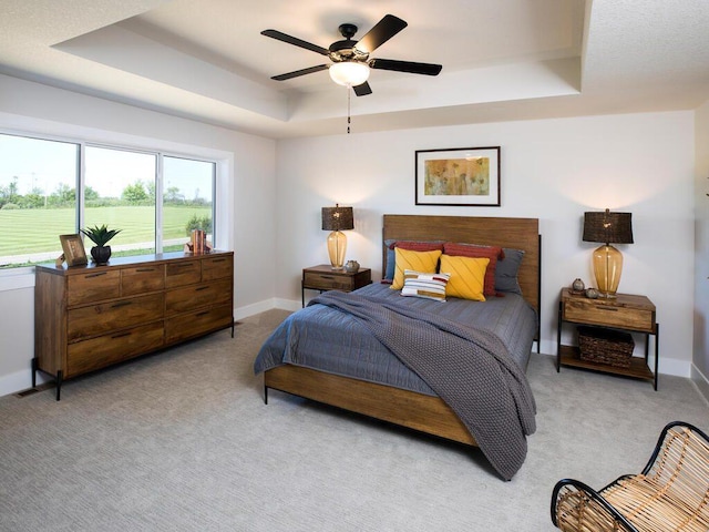 carpeted bedroom featuring a raised ceiling and ceiling fan