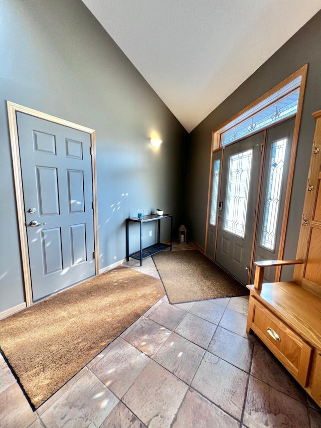 foyer entrance with tile patterned flooring and lofted ceiling