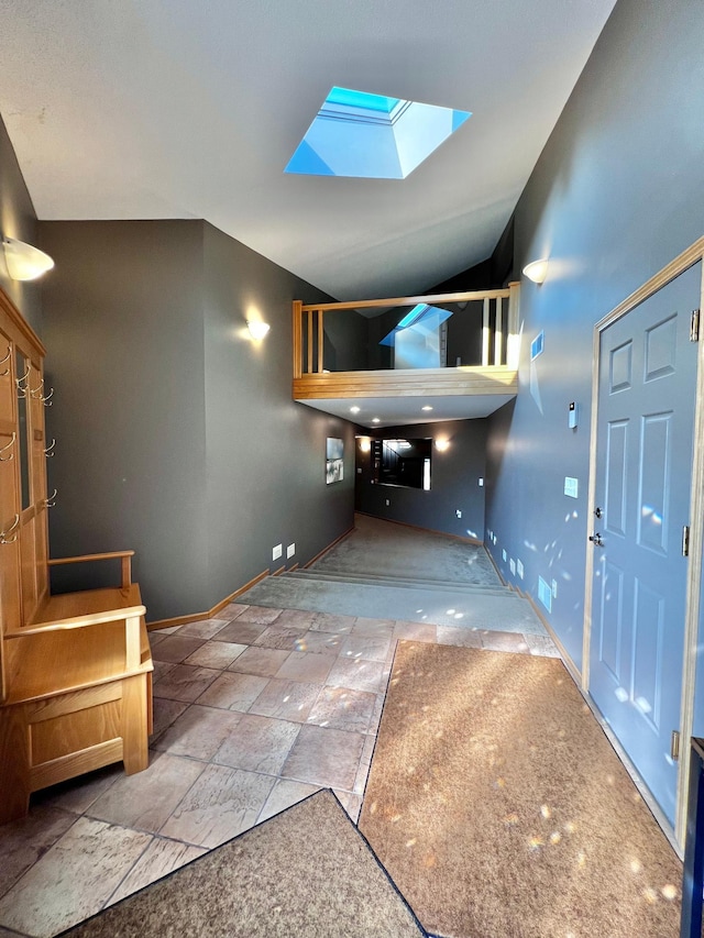 entryway featuring a skylight and high vaulted ceiling