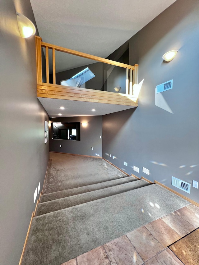 stairs featuring high vaulted ceiling and carpet floors