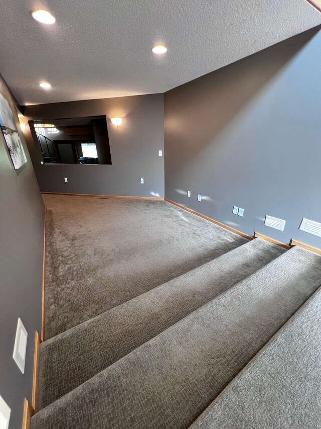 interior space with a textured ceiling and carpet flooring