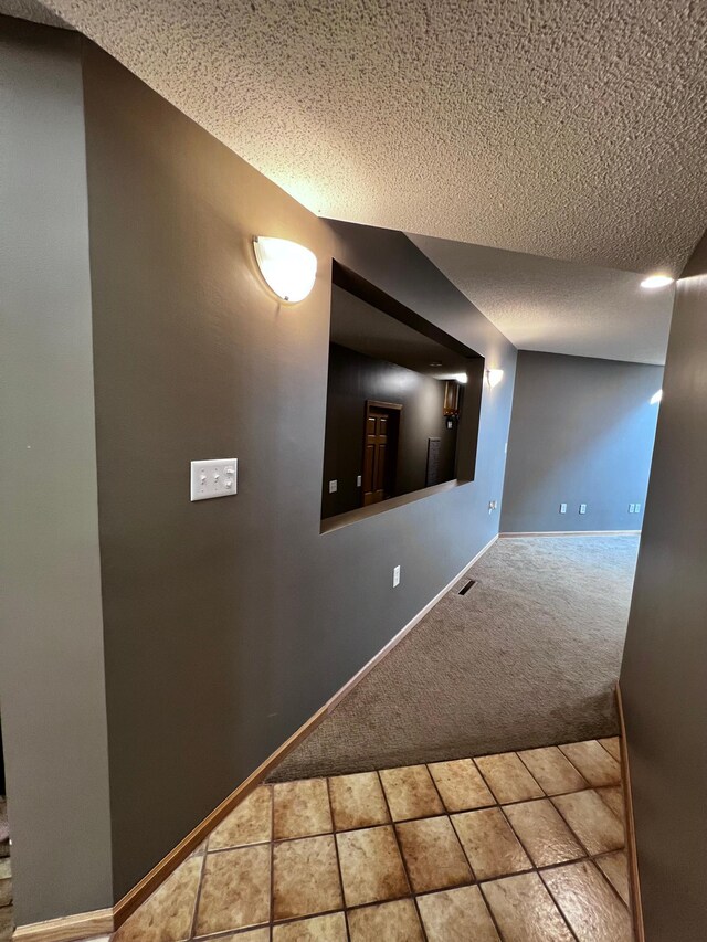 interior space with a textured ceiling and light carpet