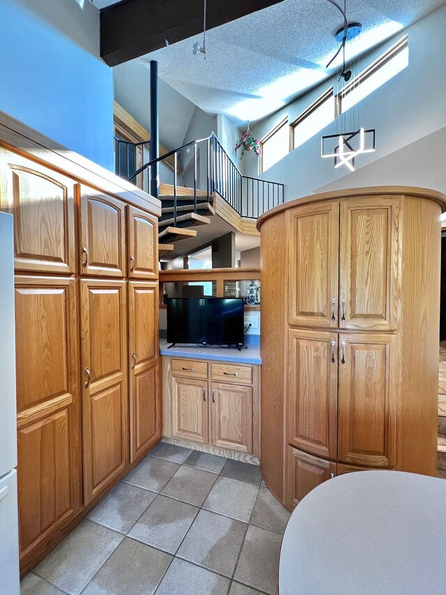 kitchen with a textured ceiling, high vaulted ceiling, and light tile patterned floors