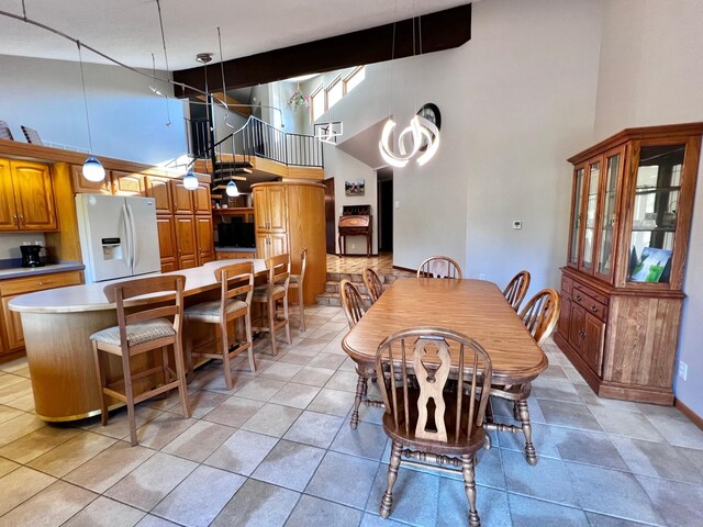 tiled dining room with beam ceiling and a towering ceiling