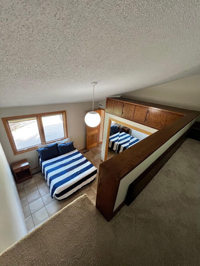 bedroom featuring a textured ceiling, lofted ceiling, and light tile patterned floors