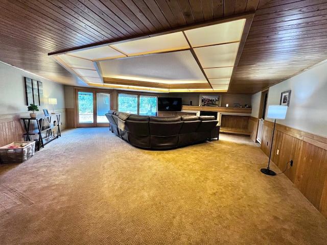 carpeted living room with wooden walls, wooden ceiling, and a raised ceiling