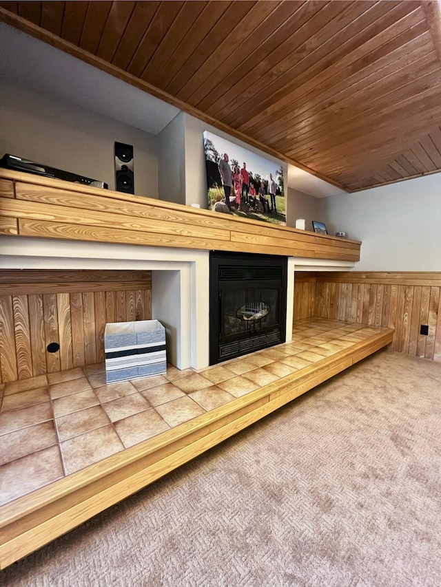 interior space with wood walls, wooden ceiling, carpet floors, and a fireplace