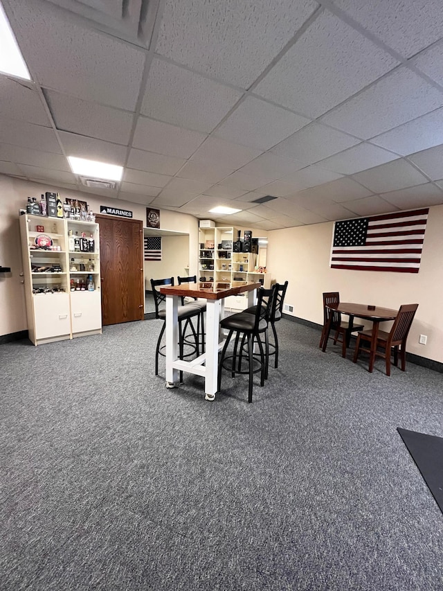 carpeted dining area with a paneled ceiling