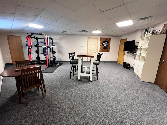 dining space with a drop ceiling and dark colored carpet