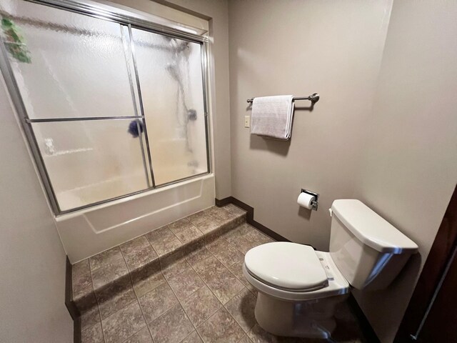 bathroom with bath / shower combo with glass door, toilet, and tile patterned flooring