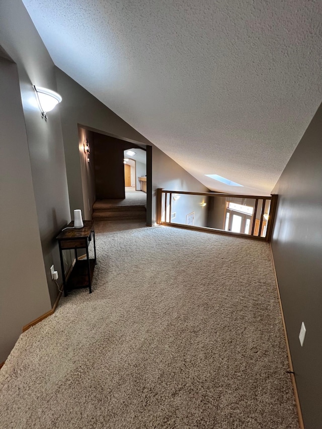 additional living space with vaulted ceiling, carpet, and a textured ceiling