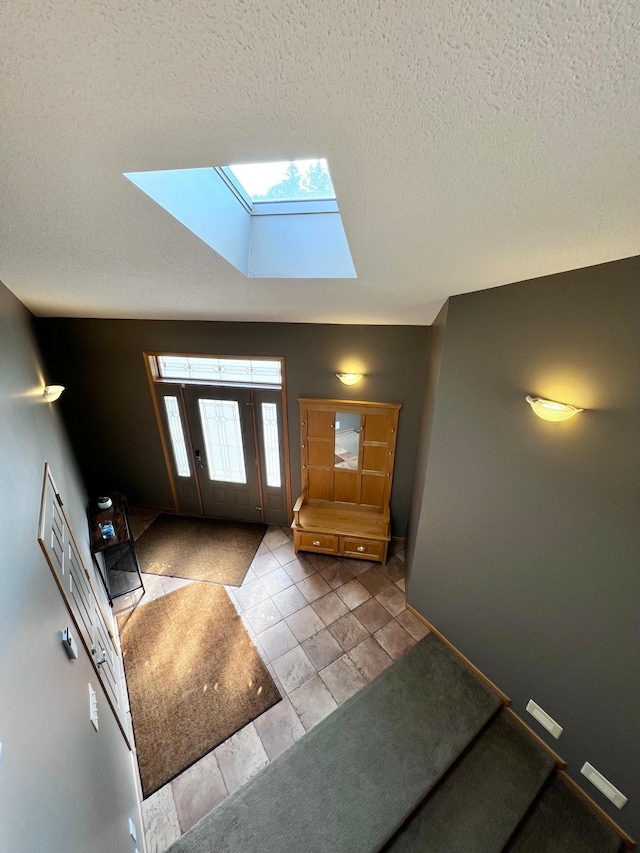 tiled foyer entrance featuring a textured ceiling and a skylight