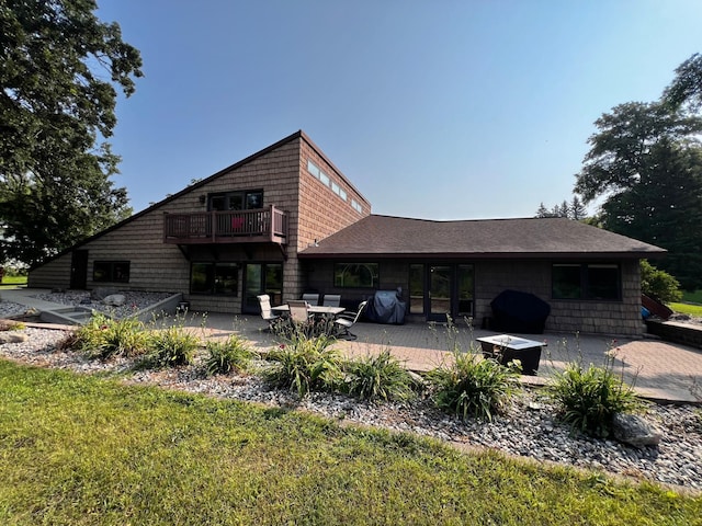 rear view of house featuring a balcony, an outdoor fire pit, a patio, and a lawn