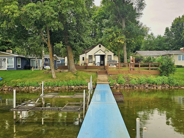 view of dock featuring a deck with water view and a yard