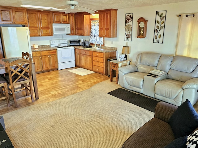 kitchen featuring ceiling fan, open floor plan, light wood-style floors, white appliances, and a textured ceiling