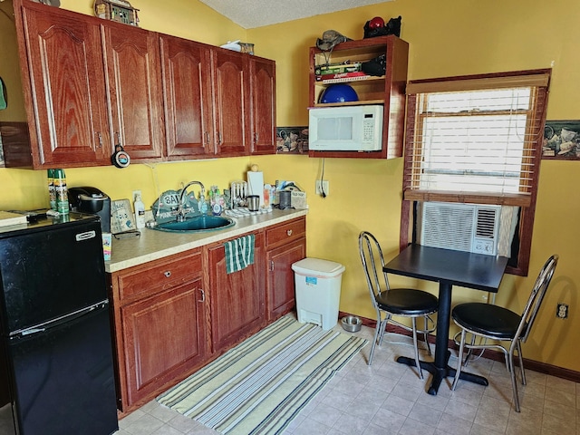 kitchen with white microwave, baseboards, freestanding refrigerator, a sink, and light countertops