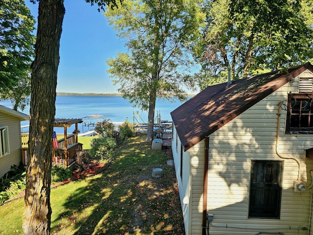 view of side of home with a yard, a water view, a shingled roof, and a pergola