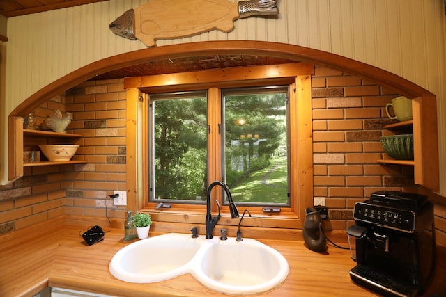 interior space featuring a bath, wood walls, wood finished floors, and a sink