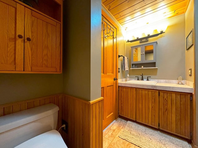 bathroom featuring wainscoting, wooden ceiling, vanity, and wood walls