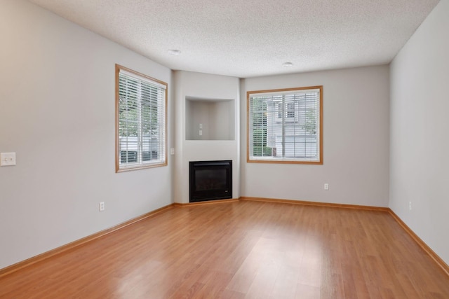 unfurnished living room with a textured ceiling and light hardwood / wood-style flooring