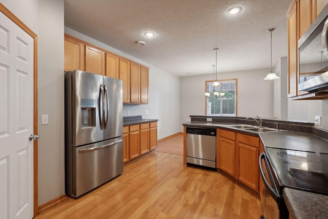 kitchen featuring appliances with stainless steel finishes, a textured ceiling, sink, pendant lighting, and a notable chandelier