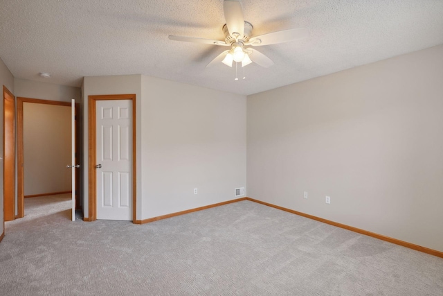 unfurnished room featuring ceiling fan, light colored carpet, and a textured ceiling