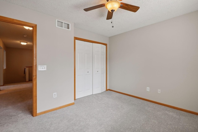 unfurnished bedroom featuring a textured ceiling, ceiling fan, light carpet, and a closet