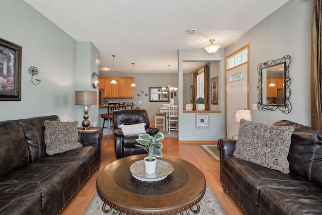 living room featuring light hardwood / wood-style floors, a textured ceiling, and an inviting chandelier