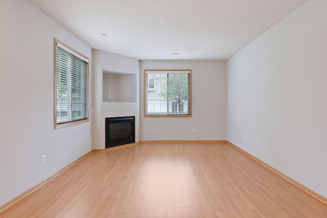 unfurnished living room with light hardwood / wood-style floors and a textured ceiling