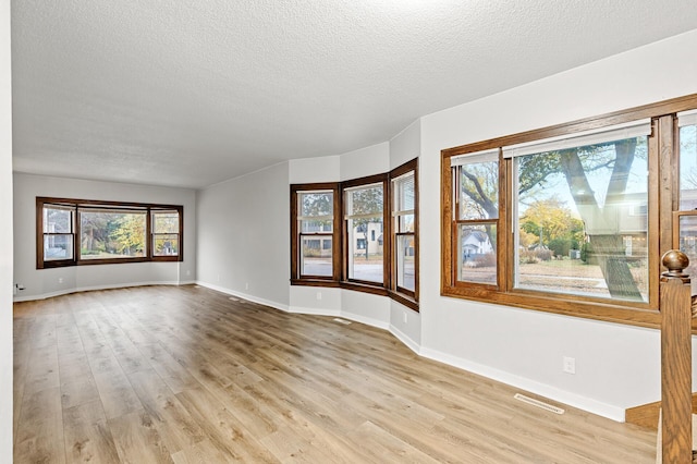 spare room with light wood-type flooring and a textured ceiling