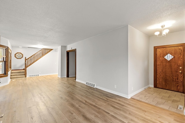 entryway featuring wood-type flooring, a chandelier, and a textured ceiling