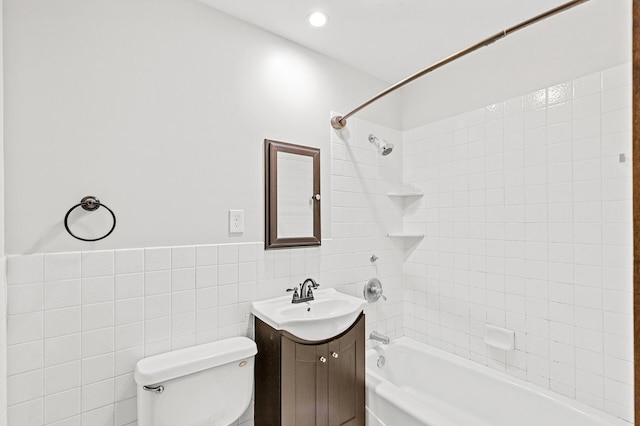 full bathroom with vanity, toilet, tiled shower / bath combo, and tile walls